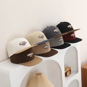 Detalle de gorras de béisbol infantiles en varios colores con bordado de HELLO