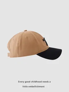 Detailed side view of khaki and black baseball cap with embroidered letters and metal buckle