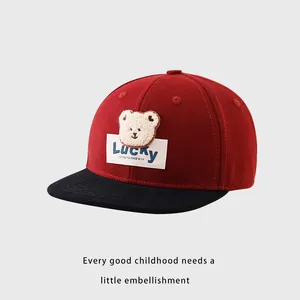 Détail d'une casquette enfant rouge avec écusson ours en peluche et broderie Lucky