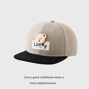 Détail de l'écusson ours LUCKY et des coutures sur la casquette bicolore pour enfant
