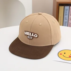 Detalle del bordado HELLO en una gorra de béisbol infantil bicolor caqui y marrón