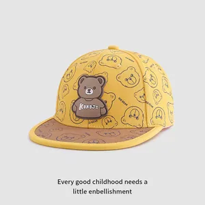 Detailed close-up of yellow cotton kids baseball cap with navy bear prints and rubber badge