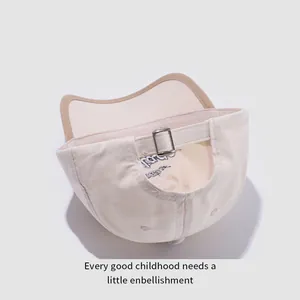 Détail de la boucle en métal réglable sur casquette enfant en coton beige avec passepoil