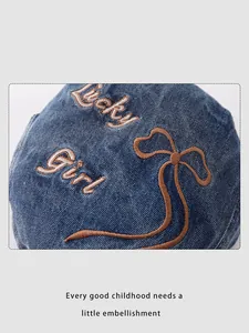Détail d'une casquette en denim bleu avec broderie Lucky Girl et motif de nœud fin