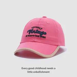 Détail d'une casquette enfant en coton rose avec broderie vintage et bordure contrastée