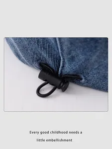 Détail du cordon de serrage avec stoppeur noir sur le bonnet en denim bleu bébé