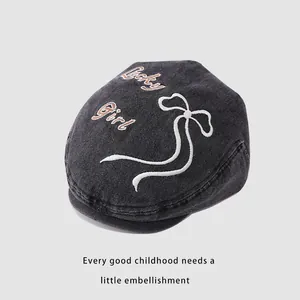 Détail de la broderie Lucky Girl et du contour du nœud sur béret en denim foncé