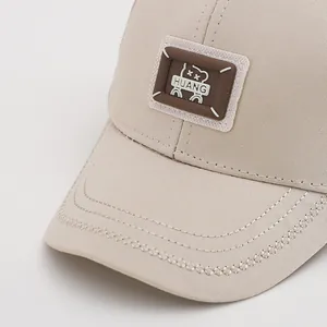 Detailaufnahme einer beigen Baby-Baseballkappe mit Silikon-Bären-Patch und feinen Nähten