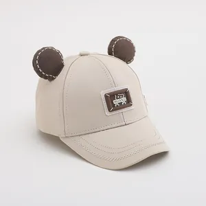 Detail der Baby-Baseballkappe mit Bärenohren, beige Stoffstruktur und süßer Stickerei