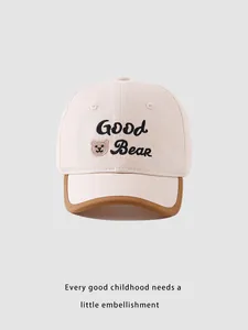 Dettaglio del ricamo Good Bear sul cappellino per bambini crema con bordo marrone
