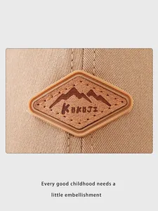 Détail du logo en cuir KUKUJI sur une casquette pour enfant en sergé de coton kaki