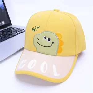 Detail van gele kinderpet met groen cartoon dinosaurus borduursel en COOL opschrift