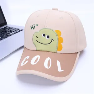 Detail van dinosaurusborduurwerk en COOL-letteropdruk op katoenen honkbalpet voor kinderen