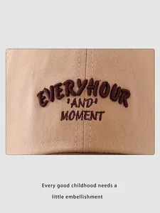 Detail of embroidered 'EVERYHOUR' text on khaki cotton kids baseball cap with twill texture