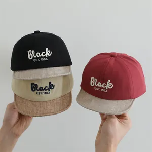 Close-up of cotton baby baseball caps with 1983 embroidery in black, khaki, and red