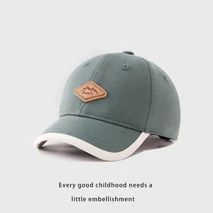 Détail de la casquette enfant vert sarcelle avec patch Kukuji et bordure blanche