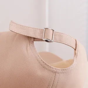Close-up of beige twill cotton baseball cap featuring an adjustable silver metal buckle
