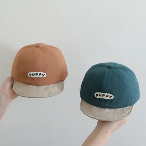 Detail of baby baseball caps in brown and green with PUPPY patch and soft beige brim