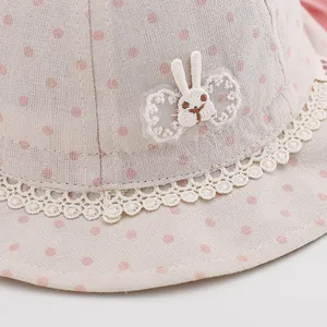 Detail of baby sun hat featuring pink polka dots, lace trim, and rabbit embroidery