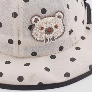 Cute beige polka dot baby sun hat with teddy bear embroidery and black bow detail