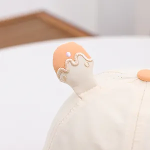 Close-up of beige baby sun hat featuring orange 3D accents and breathable cotton mesh fabric