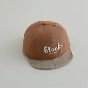 Detailed close-up of brown baby baseball cap with Black embroidery and textured soft brim