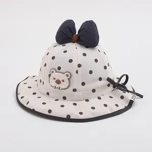 Detailed view of polka dot sun hat featuring a large navy bow and bear embroidery