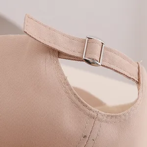 Détail de la boucle métallique et de la sangle réglable sur une casquette en coton rose