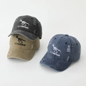 Close-up of three distressed baseball caps with dinosaur embroidery and frayed details