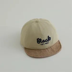 Close-up of baby baseball cap with Black EST. 1983 embroidery and straw textured brim