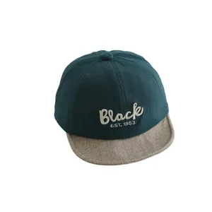 Kids baseball cap in dark green with beige woven brim and Black 1983 embroidery