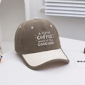 Detailed close-up of white letter embroidery on two-tone brown and beige cotton baseball cap