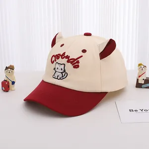 Détail d'une casquette enfant beige et bordeaux avec oreilles de chat et broderie Studio