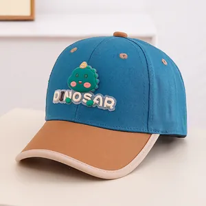 Detail of blue and brown kids baseball cap with a green dinosaur patch and beige trim