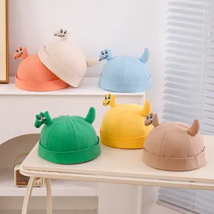 Dettaglio di cappelli docker colorati in cotone con decorazioni di dinosauri 3D per bambini