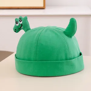 Dettaglio del ricamo a dinosauro su un berretto in cotone verde per bambini