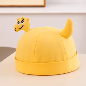 Dettaglio del cappello da dinosauro in cotone giallo con ricami e corna 3D