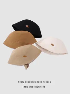 Detailed view of four cotton bucket hats in neutral tones with cloud shaped leather labels