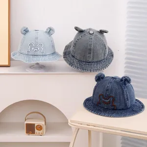 Detail of three denim baby sun hats with cute bear ears and facial embroidery
