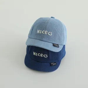 Close-up of denim baby baseball caps showing texture and white embroidered smile logo