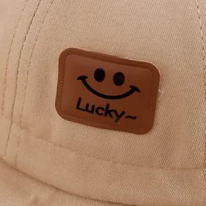 Gros plan du chapeau bob en coton kaki avec écusson en cuir Lucky smiley face