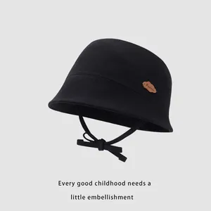 Detail of black cotton canvas kids bucket hat with chin strap and brown cloud leather patch