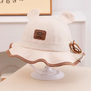 Détail du chapeau bob bébé en coton avec oreilles d'ours et patch smiley Lucky