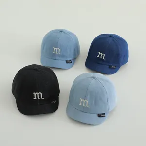 Detail of baby denim baseball caps with embroidered M logo in four different color shades