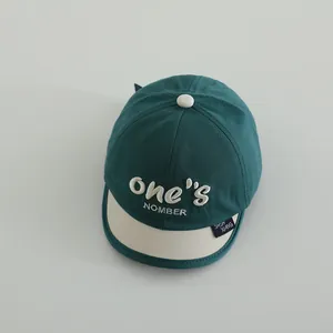 Detalle de gorra bicolor para niño verde oscuro y crema con bordado 3D de calidad