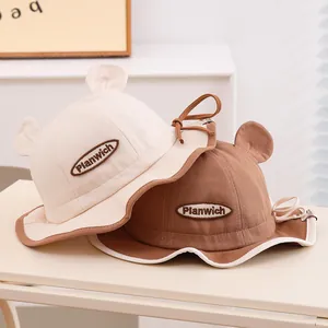 Détail de chapeaux de soleil pour bébé en beige et café avec oreilles mignonnes et bride