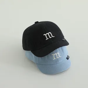 Close-up of washed denim baby baseball caps with m embroidery in blue and black