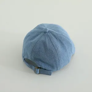 Detail of adjustable metal buckle and denim strap on the back of light blue baby cap