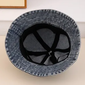 Detail view of denim bucket hat interior with reinforced black tape and metal top button