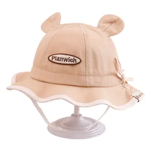 Détail chapeau bébé avec oreilles d'ours, nœud papillon et broderie Planwich douce